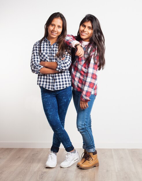 Young girl with arms crossed while another is leaning on her