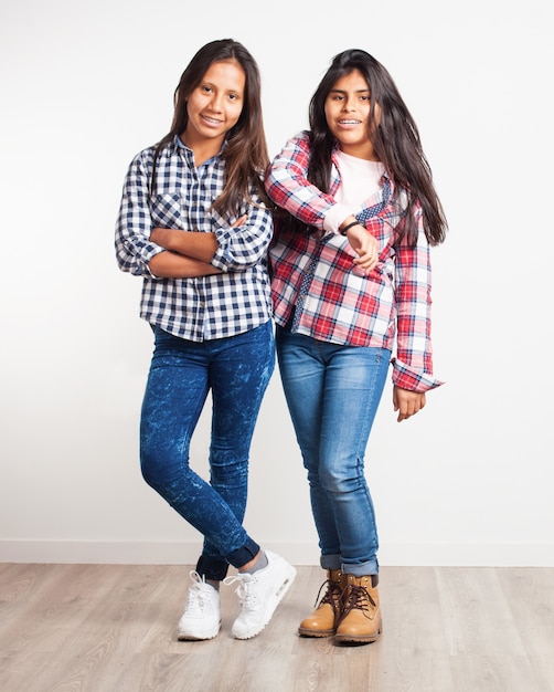 Young girl with arms crossed while another is leaning on her