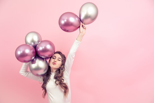 Young girl with balloons on a colored wall