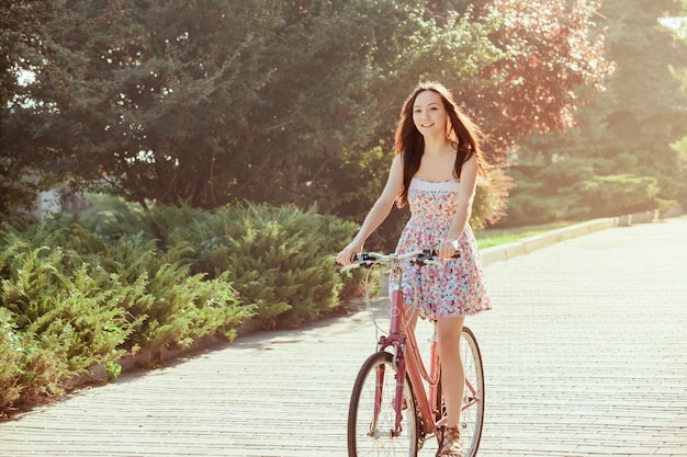 Молодая девушка с велосипедом в парке