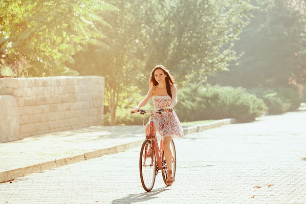 Молодая девушка с велосипедом в парке