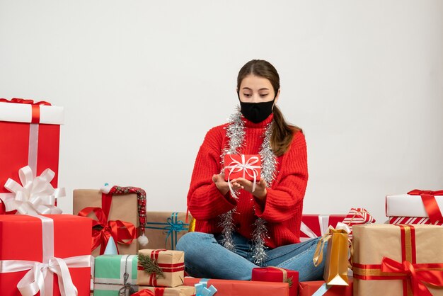 young girl with black mask looking at her gift sitting around presents on white