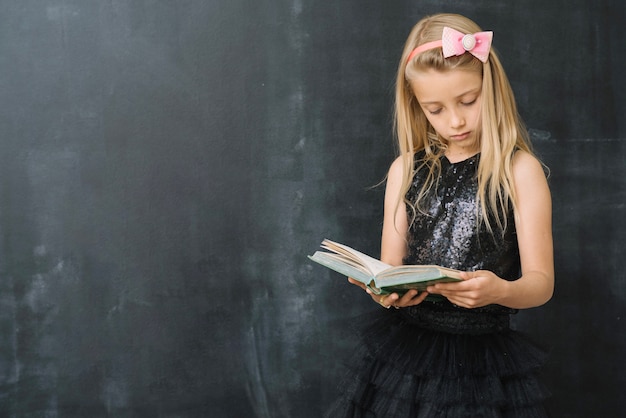 Young girl with book at chalkboard