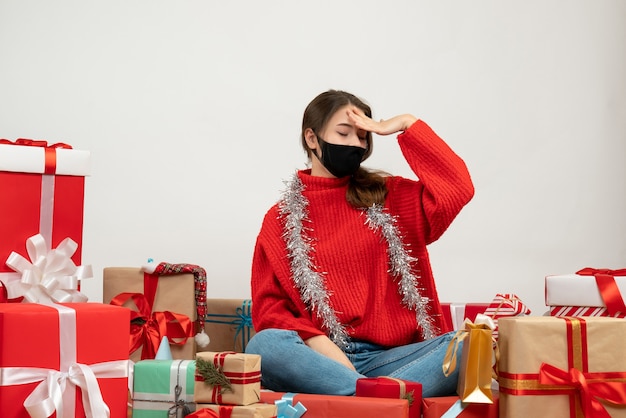 Free photo young girl with closed eyes sitting around presents on white