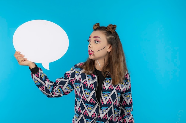 Free photo young girl with creative makeup holding idea board on blue background. high quality photo