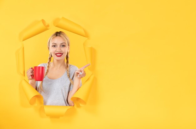 Young girl with cup of tea on a torn yellow paper surface