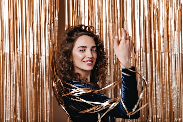 Young girl with curly hair posing among gold decorations