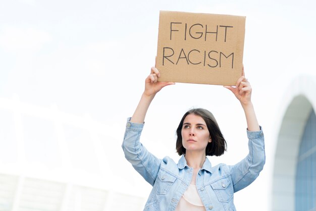 Young girl with fight racism quote on cardboard