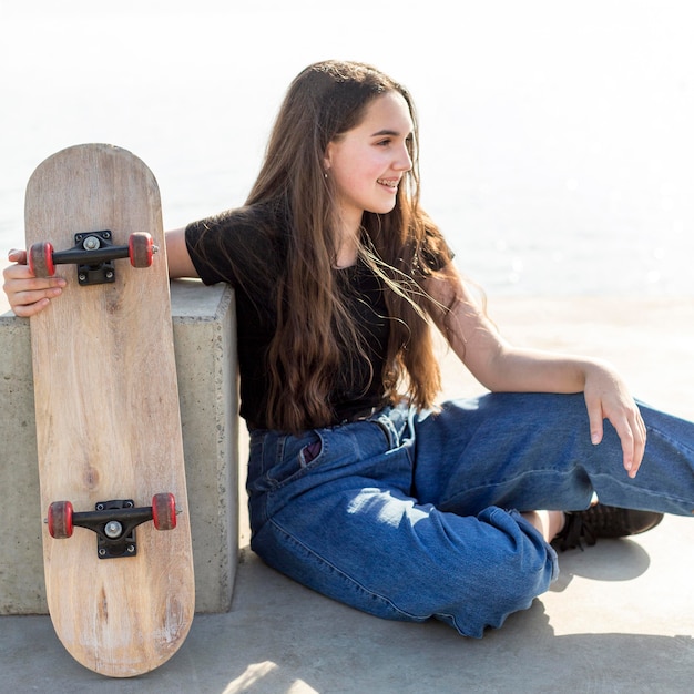 彼女のスケートボードを屋外に保持している長い髪の少女