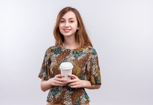 Young girl with long hair wearing colorful dress holding coffee cup smiling confident 