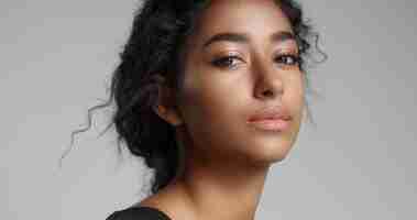 Free photo young girl with perfect light brown skin and beautiful curly black hair smiling at the camera in studio