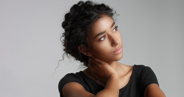 Free photo young girl with perfect light brown skin and beautiful curly black hair smiling at the camera in studio