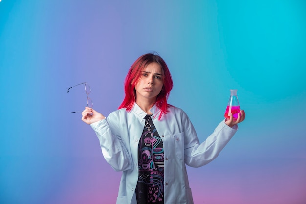 Young girl with pink hairs holding a chemical flask and looks confused.