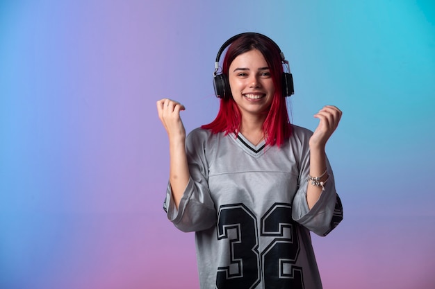 Free photo young girl with pink hairs looks positive and wearing headphones.