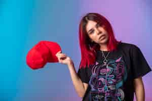 Free photo young girl with pink hairs taking out a red cap.