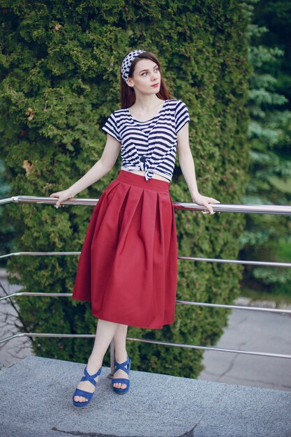 Young girl with red skirt leaning on a white metal railing