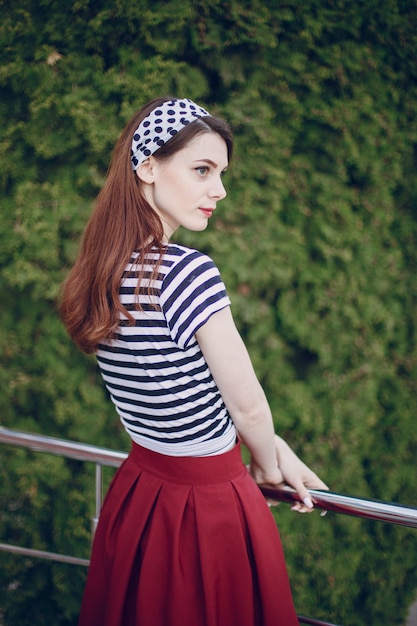 Young girl with red skirt leaning on a white metal railing