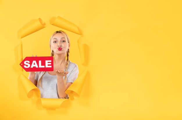 Free photo young girl with sale inscription sign on torn yellow desk fashion shopping indoor