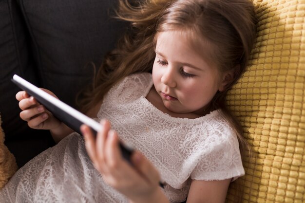 Young girl with tablet on couch