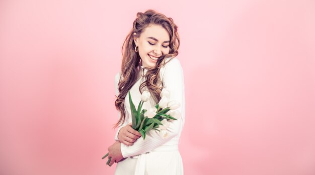 Young girl with tulips on a colored wall