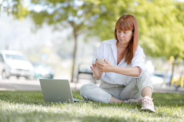 Молодая девушка работает за компьютером в парке