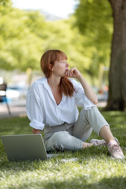 公園でコンピューターに取り組んでいる少女