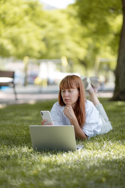 公園でコンピューターに取り組んでいる少女