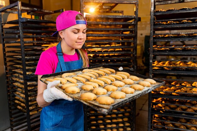 Молодая девушка работает с пекарней на фабрике. женский шеф-повар в пекарне.
