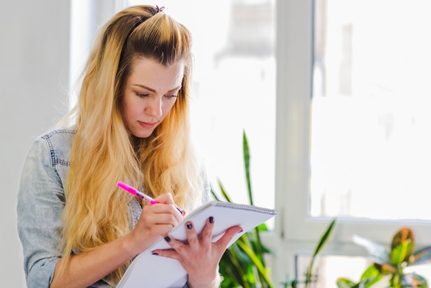 Free photo young girl writing in notepad