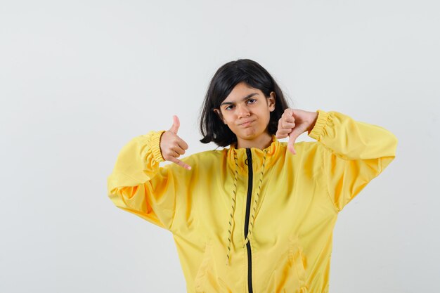 Young girl in yellow bomber jacket showing thumb down and call me gesture and looking serious