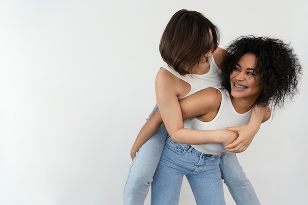 Young girlfriends enjoying the time together with piggy back ride