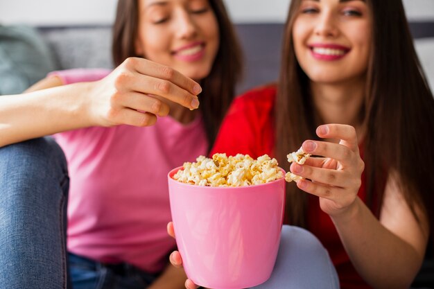 Young girlfriends at home eating popcorn