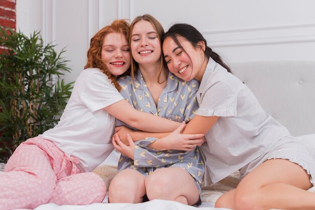 Young girlfriends hugging in bed