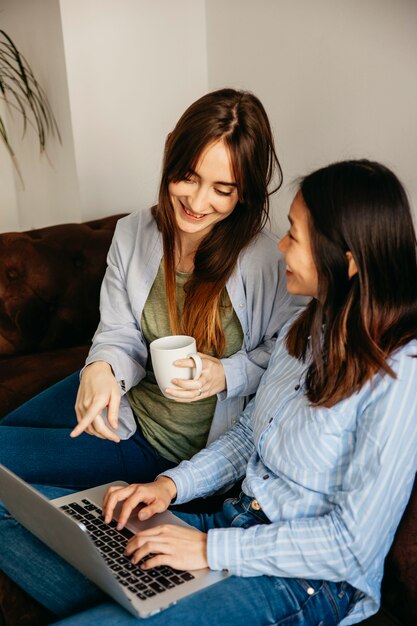 Young girls chilling with laptop on sofa