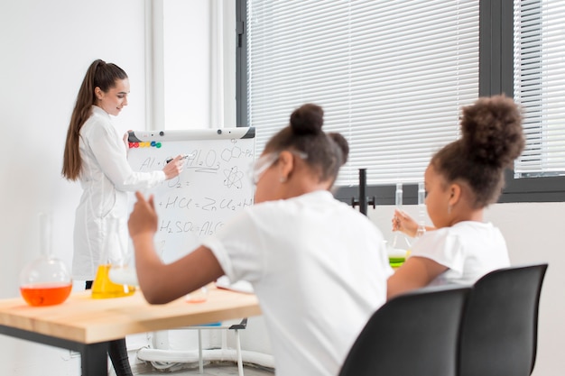 Young girls learning about chemistry from female scientist