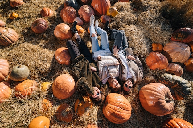 Young girls lie on haystacks among pumpkins. View from above