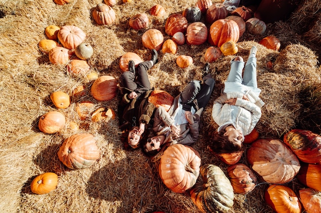 Young girls lie on haystacks among pumpkins