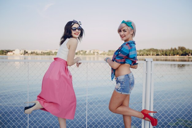Young girls posing with one leg lifted on a white fence