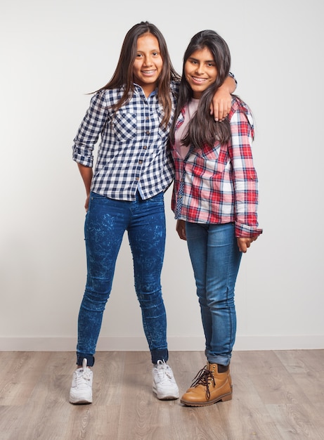 Young girls standing smiling and one with one arm above the other