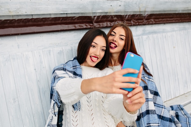 Young girls taking a photo with a blue mobile phone