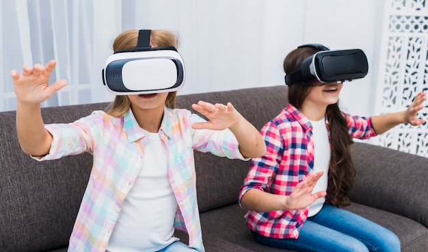 Free photo young girls using a virtual reality headset touching their hands in the air