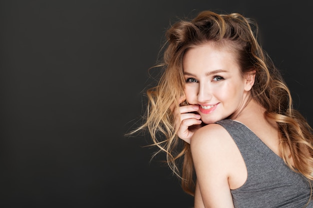 Young gorgeous woman posing over dark wall