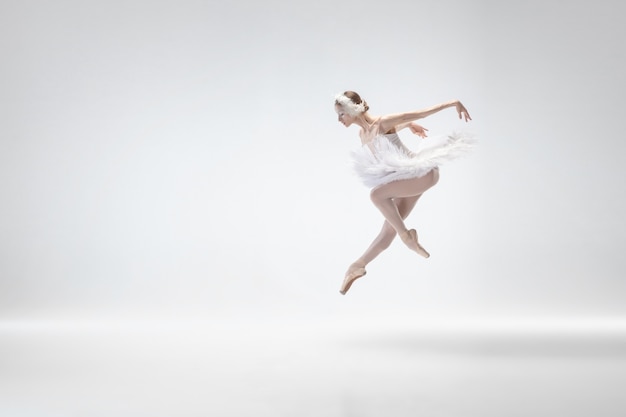 Young graceful ballerina on white studio background