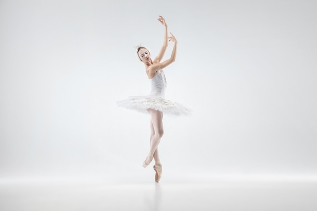 Young graceful ballerina on white studio background