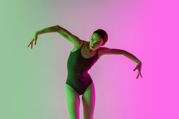 Young and graceful ballet dancer isolated on gradient pink-green studio wall