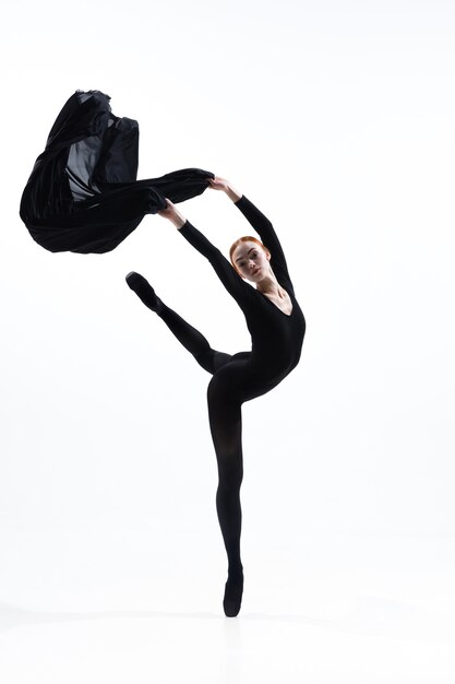 Молодой и изящный артист балета в минимальном черном стиле, изолированные на белом фоне студии. Искусство, движение, действие, гибкость, концепция вдохновения.