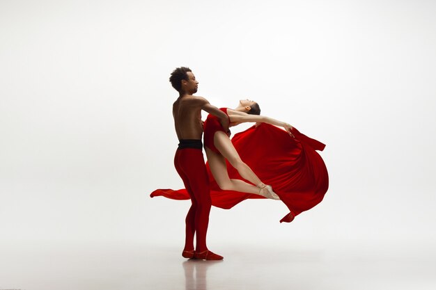 Young graceful couple of ballet dancers dancing on white studio background