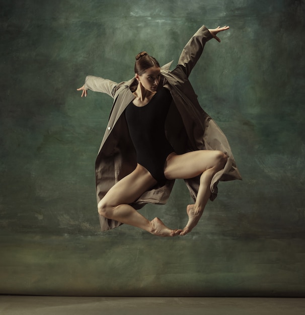 Young graceful tender ballerina on dark studio