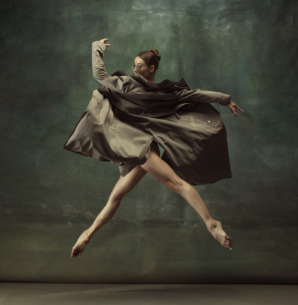 Young graceful tender ballerina on dark studio