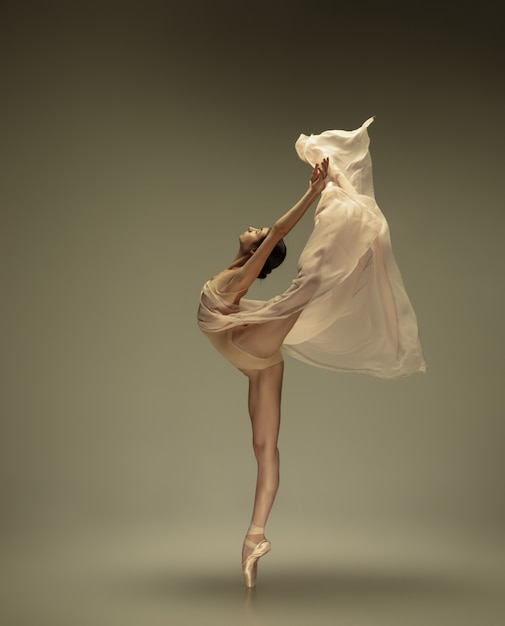 Young graceful tender ballerina on pastel wall